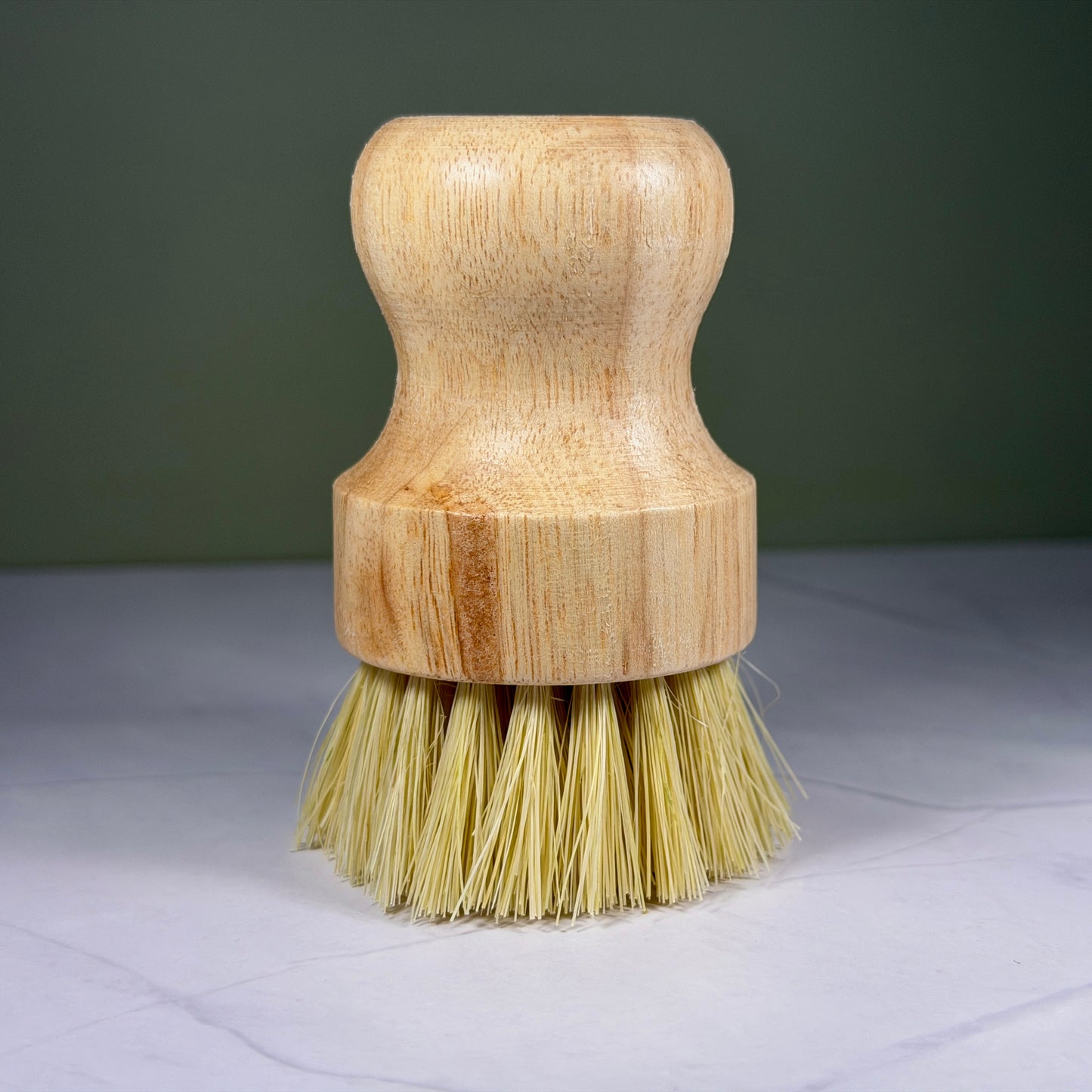 Wooden dish brush with bristle head on a gray surface and dark background