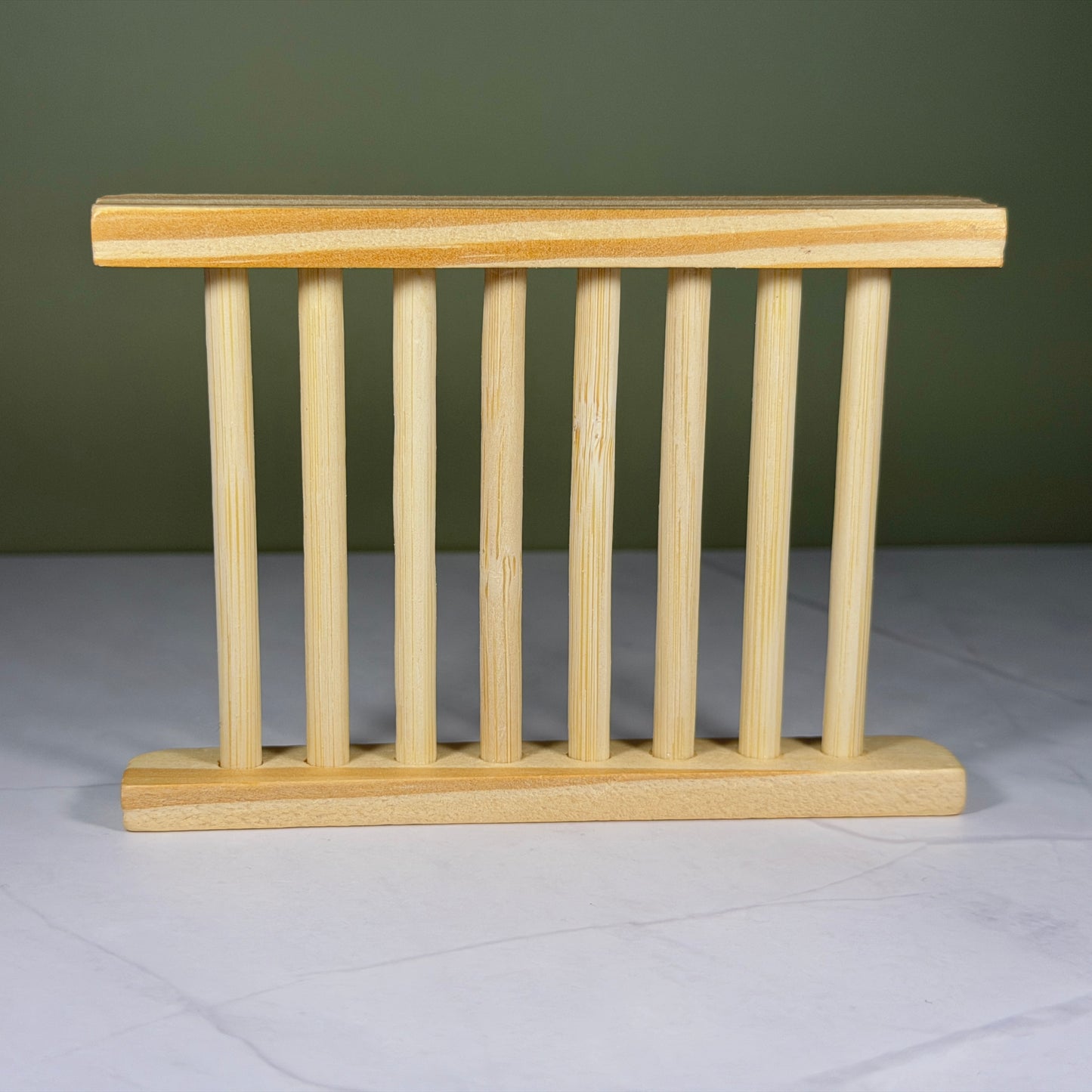 Wooden soap dish on a white surface with a green background