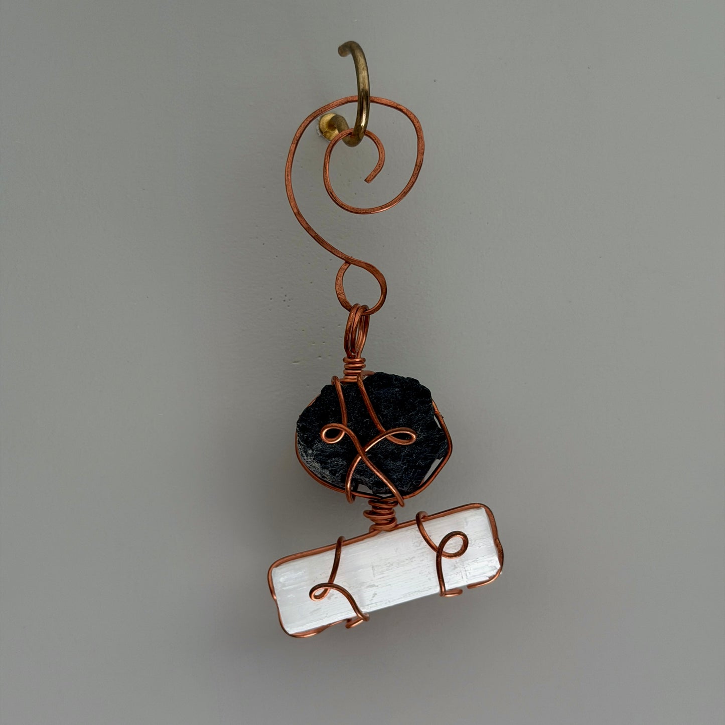 Handmade pendant with black stone and white stone on a gray background
