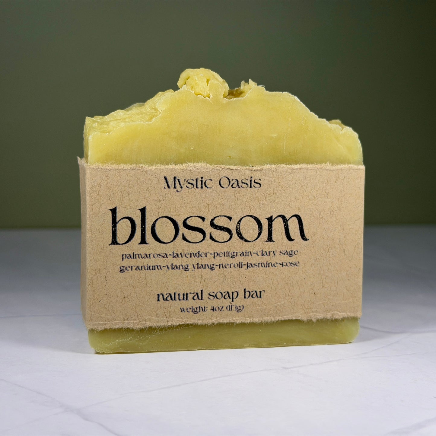 Mystic Oasis blossom natural soap bar on a white surface with a green background