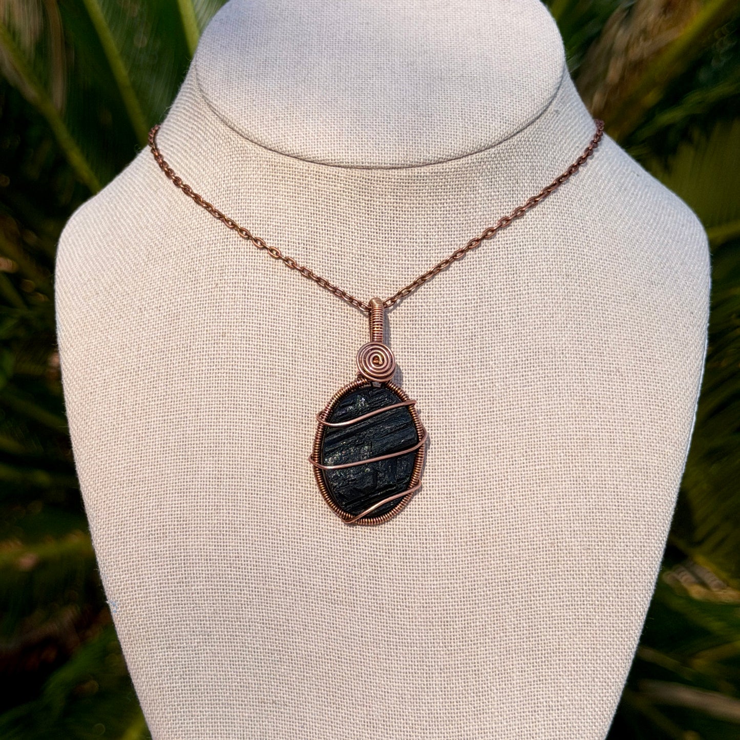Necklace with a black pendant on a mannequin bust against a natural background