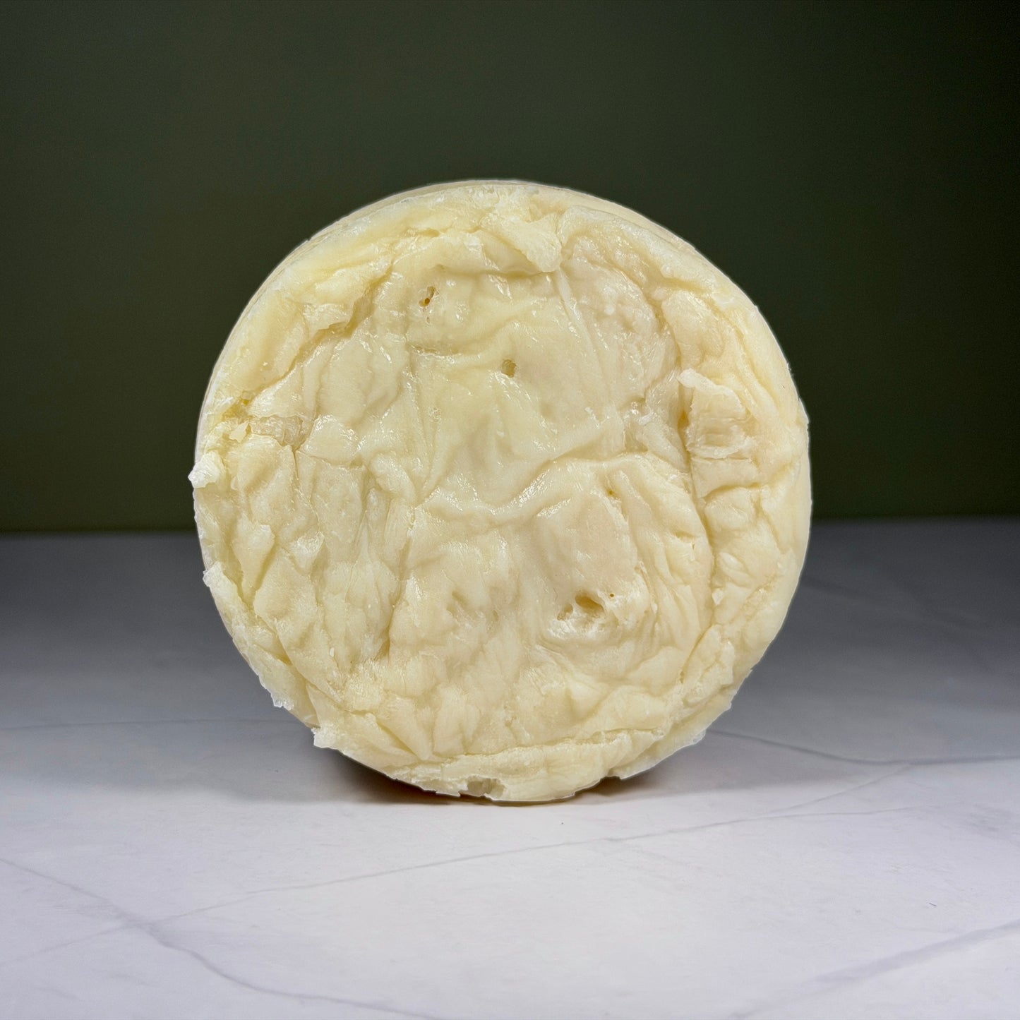 Round block of soap on a white surface with a dark background