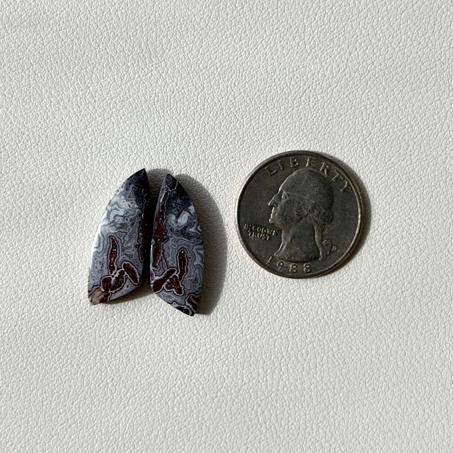 pair of agate stones next to a U.S. quarter on a light gray background
