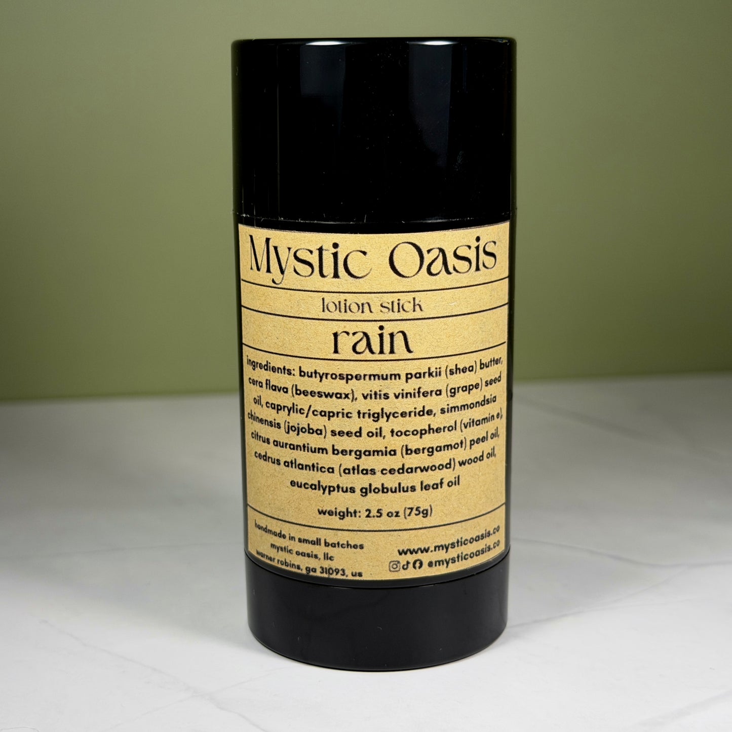 Mystic Oasis lotion stick labeled 'rain' on a white surface with a green background