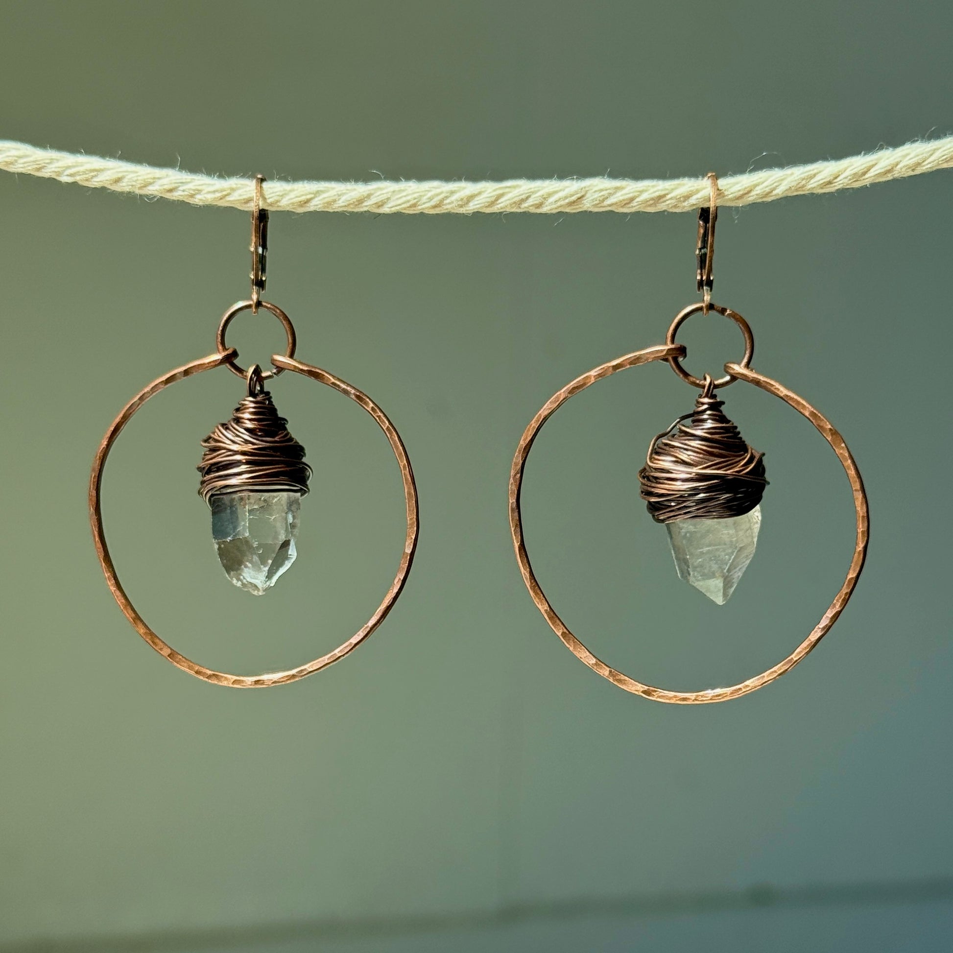 Pair of earrings with circular designs and crystal elements on a neutral background