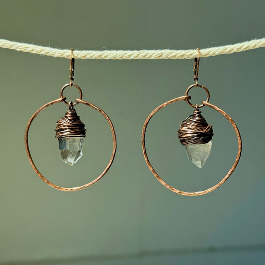 Pair of earrings with circular designs and crystal elements on a neutral background