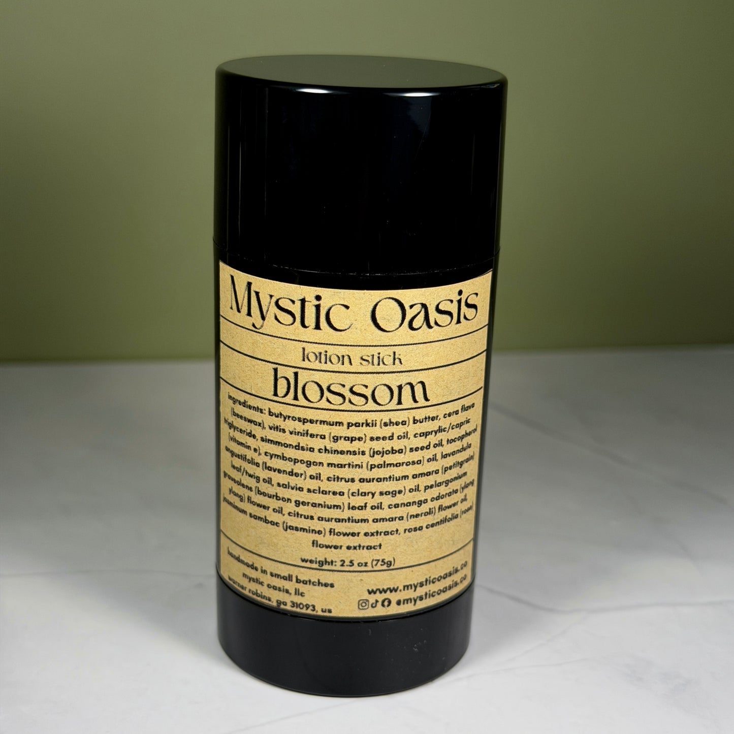 Black lotion stick labeled 'Mystic Oasis' on a white surface with a green background