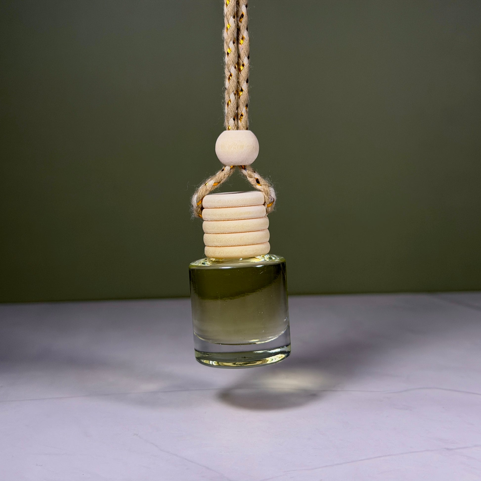 Glass diffuser with wooden beads hanging against a green background