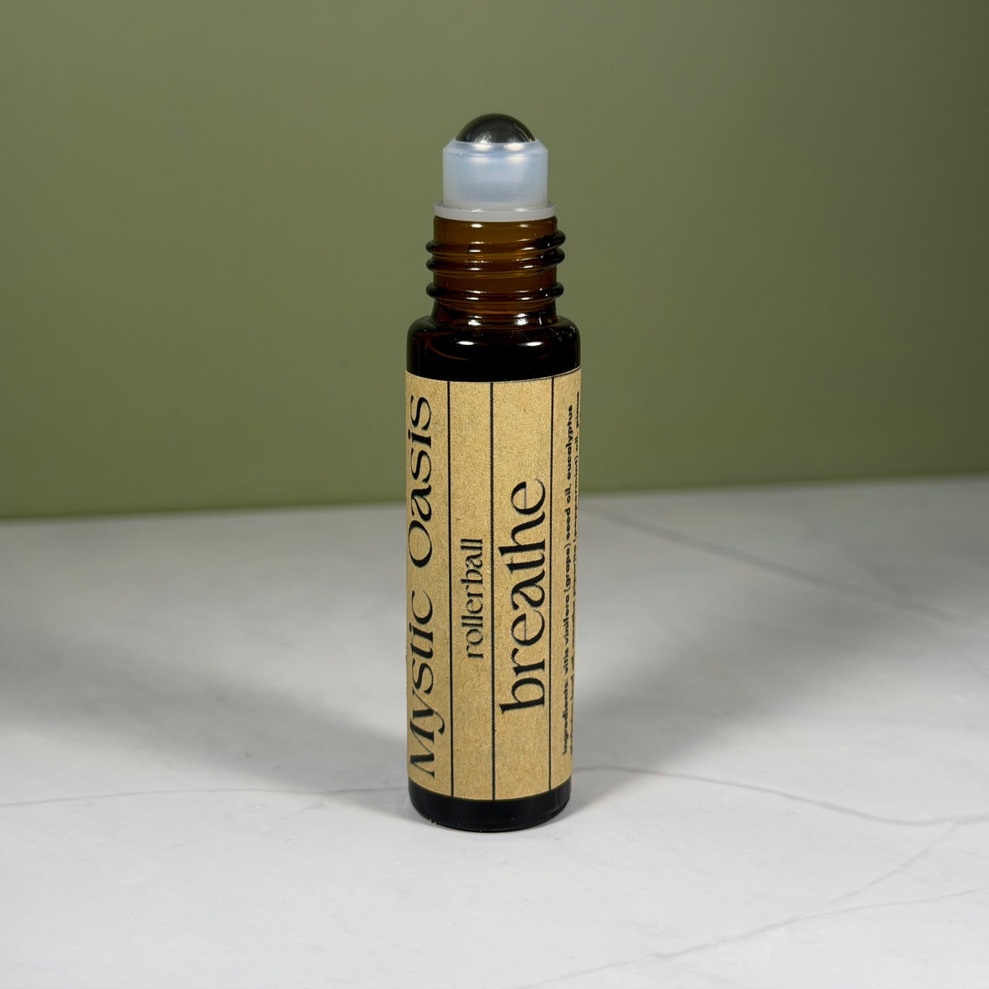 Rollerball bottle labeled 'Mystic Oasis breathe' on a light surface with a green background
