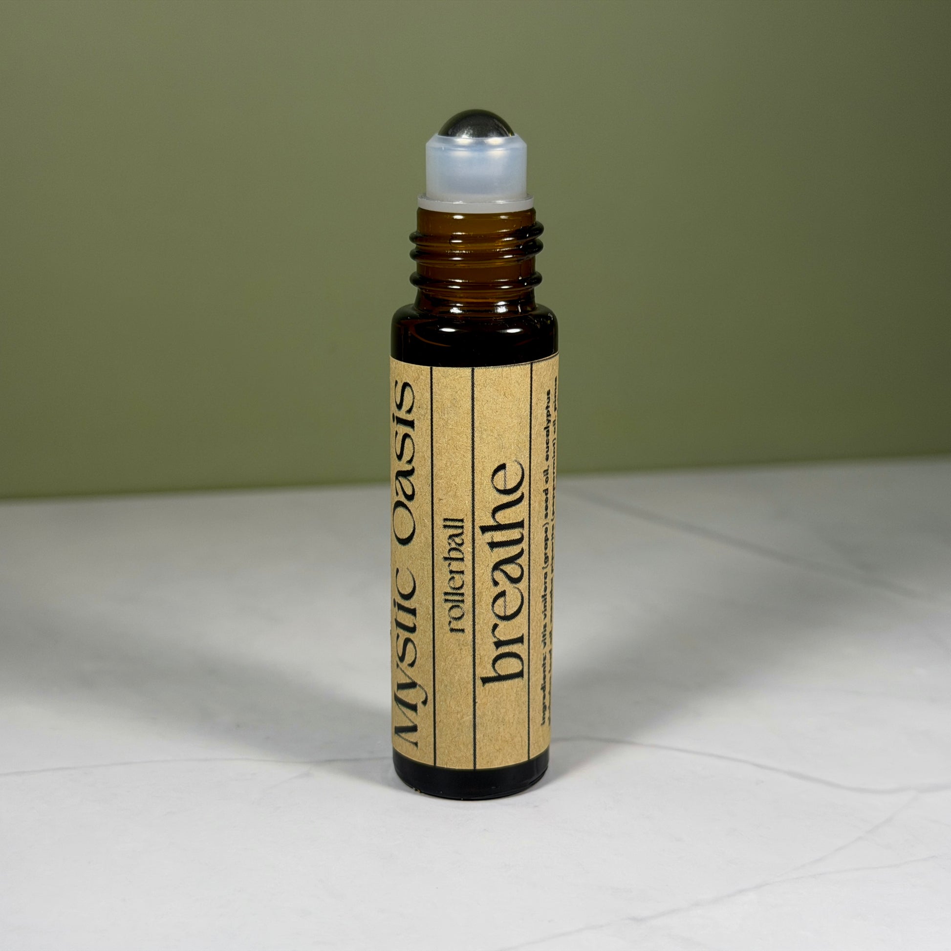 Rollerball bottle labeled 'Mystic Oasis breathe' on a light surface with a green background