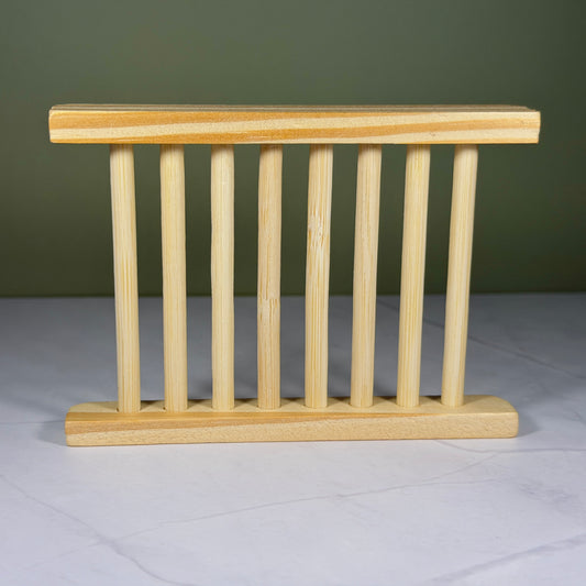 Wooden soap dish on a white surface with a green background