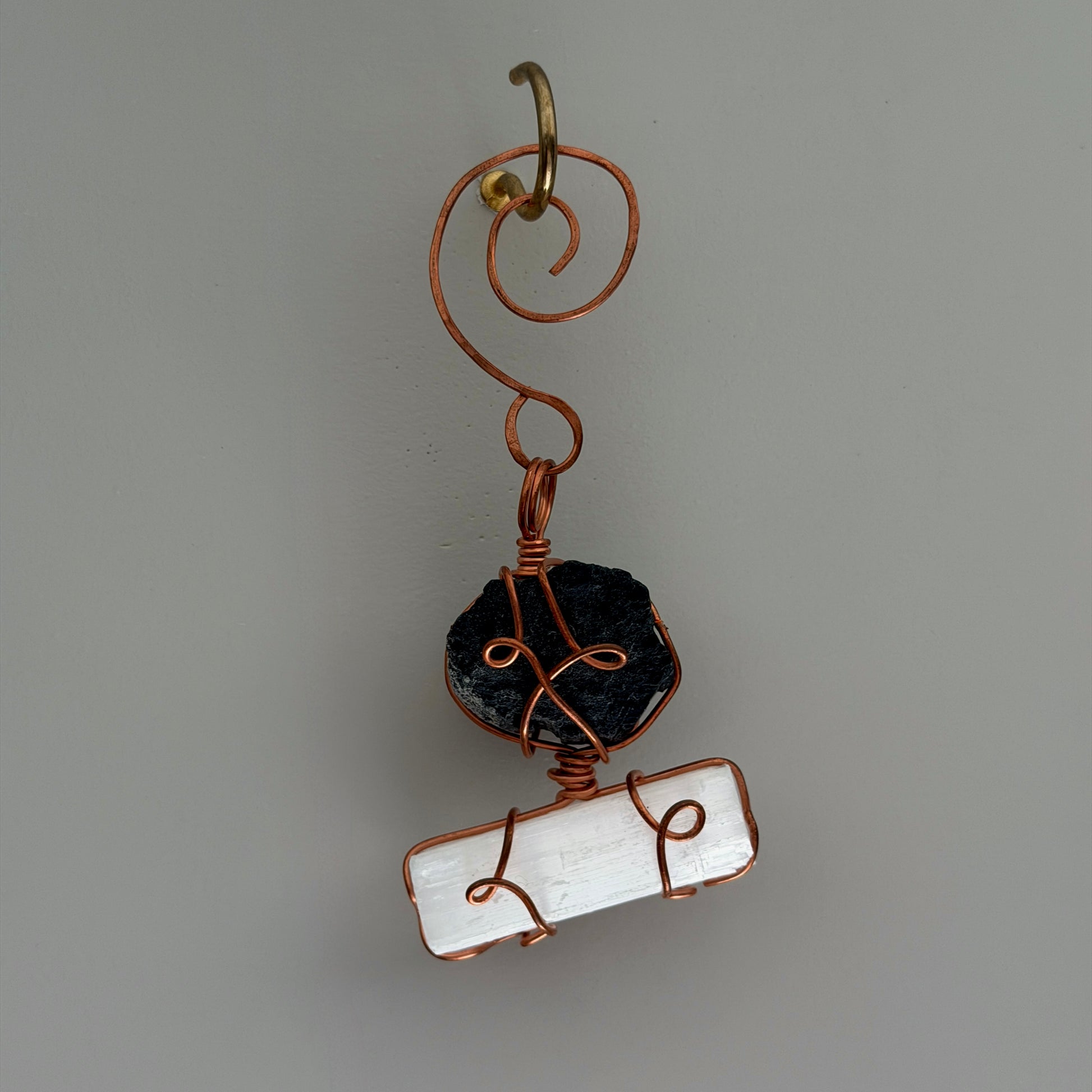 Handmade pendant with black stone and white stone on a gray background