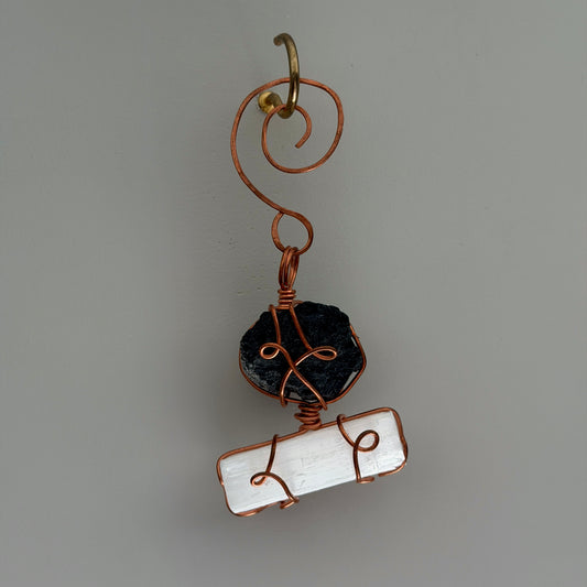 Handmade pendant with black stone and white stone on a gray background