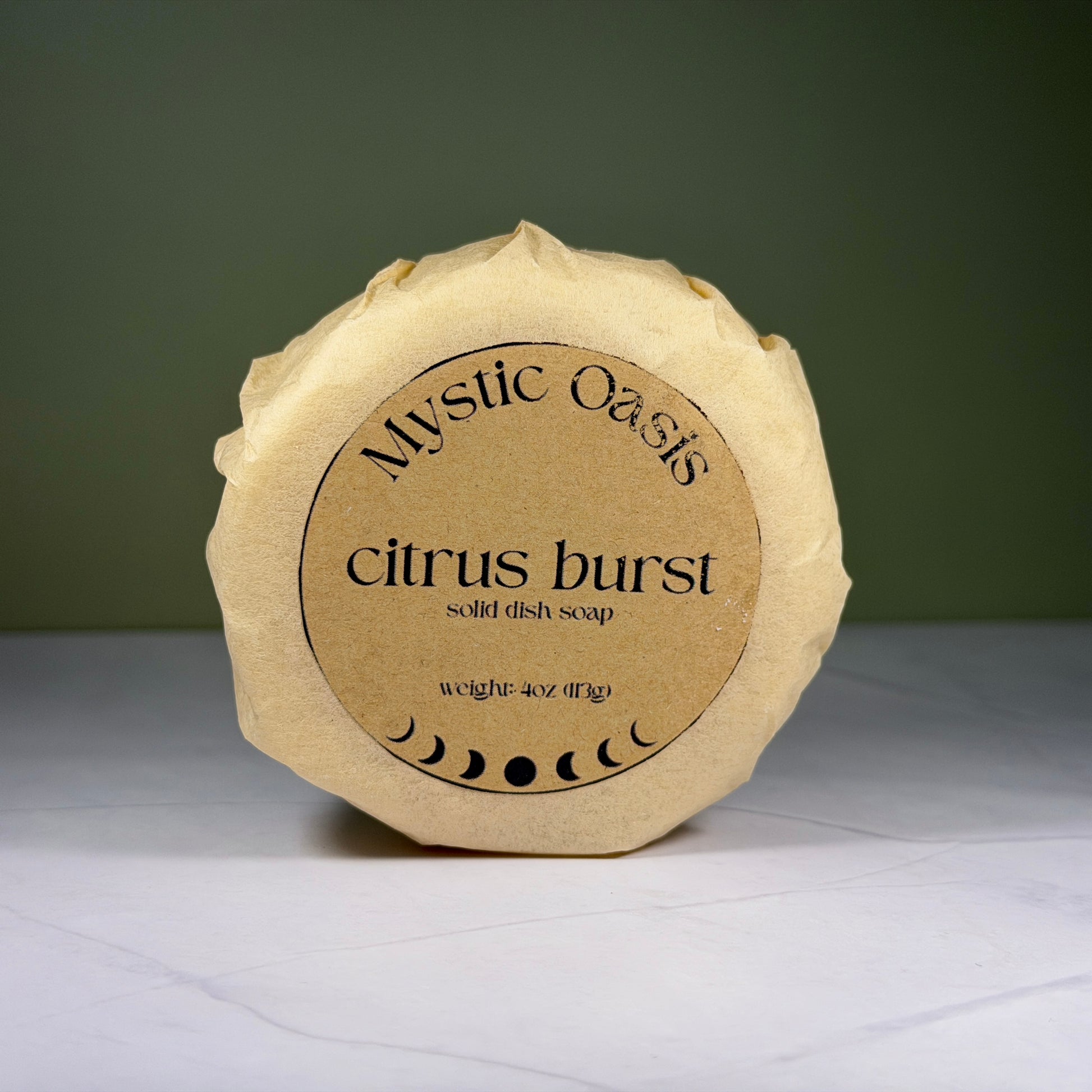 Mystic Oasis citrus burst solid dish soap on a white surface with a green background