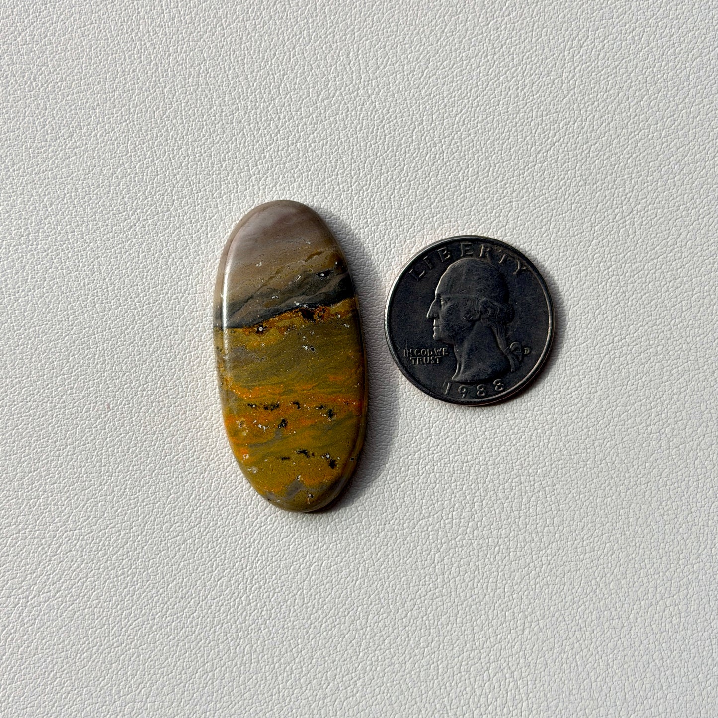 Oval-shaped stone next to a U.S. quarter on a light gray background