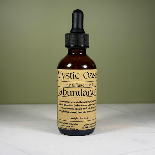 Mystic Oasis abundance car diffuser refill bottle on a light surface with a green background