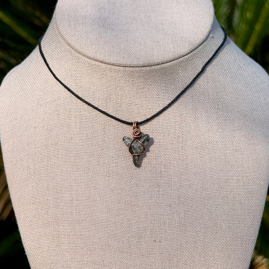 Necklace with a shark tooth pendant on a mannequin bust against a natural background
