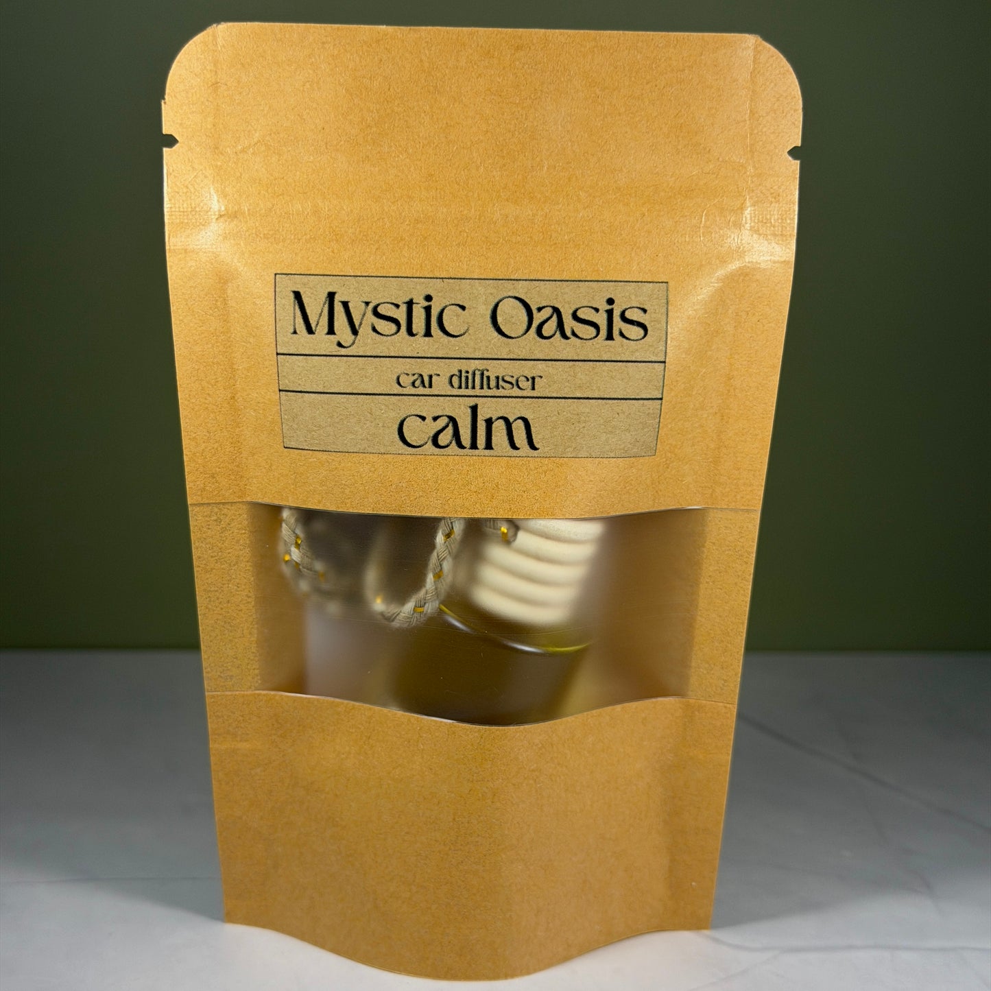 Kraft paper packaging with 'Mystic Oasis' car diffuser labeled 'calm' on a gray background