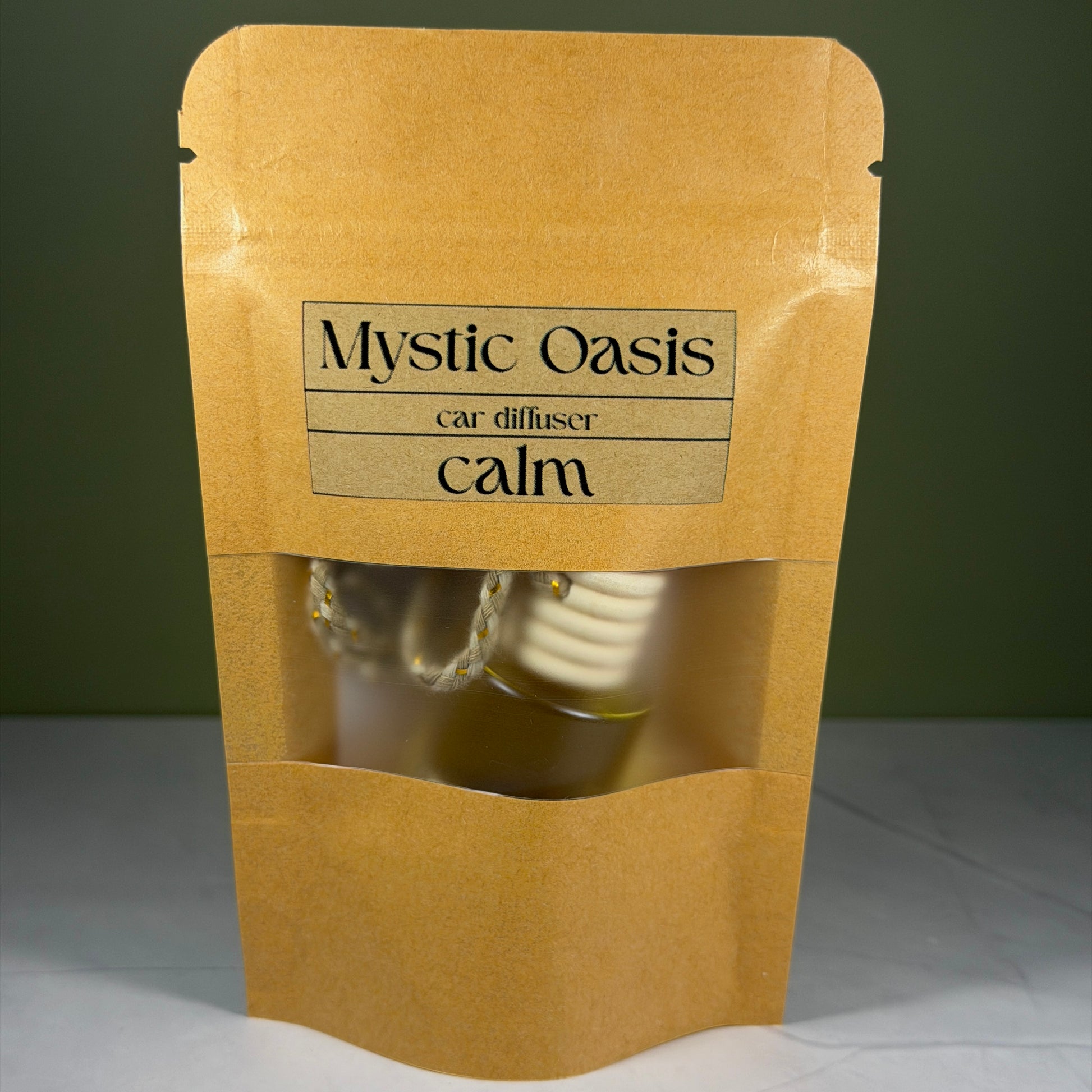 Kraft paper packaging with 'Mystic Oasis' car diffuser labeled 'calm' on a gray background