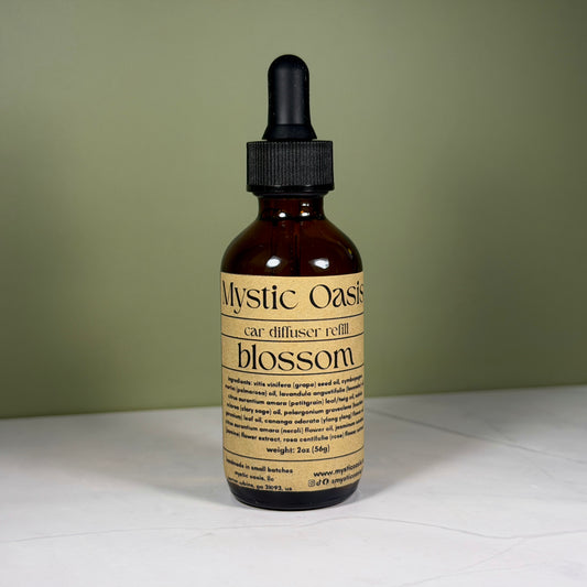 Mystic Oasis car diffuser refill bottle with dropper on a white surface and green background