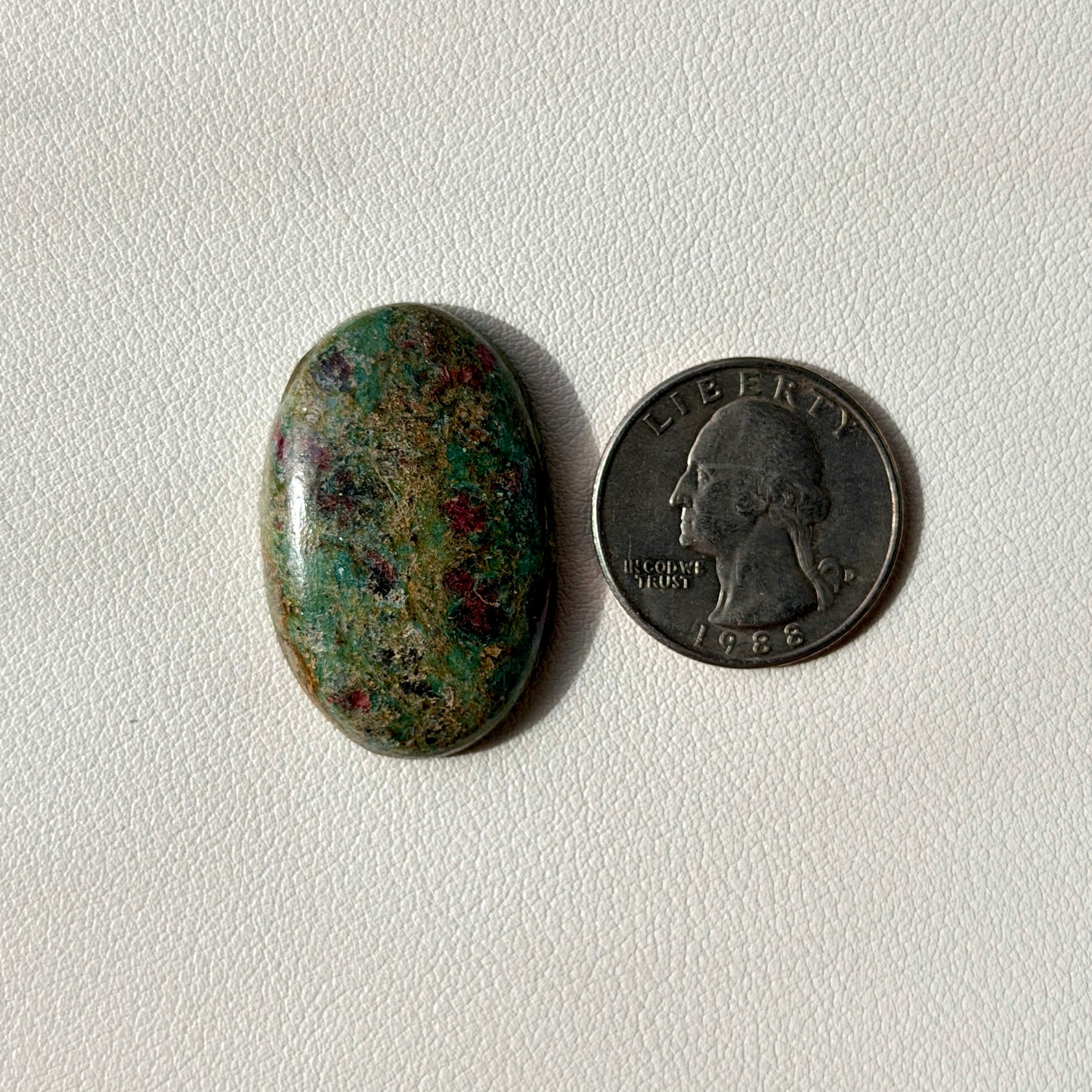 Oval stone next to a U.S. quarter on a light gray background