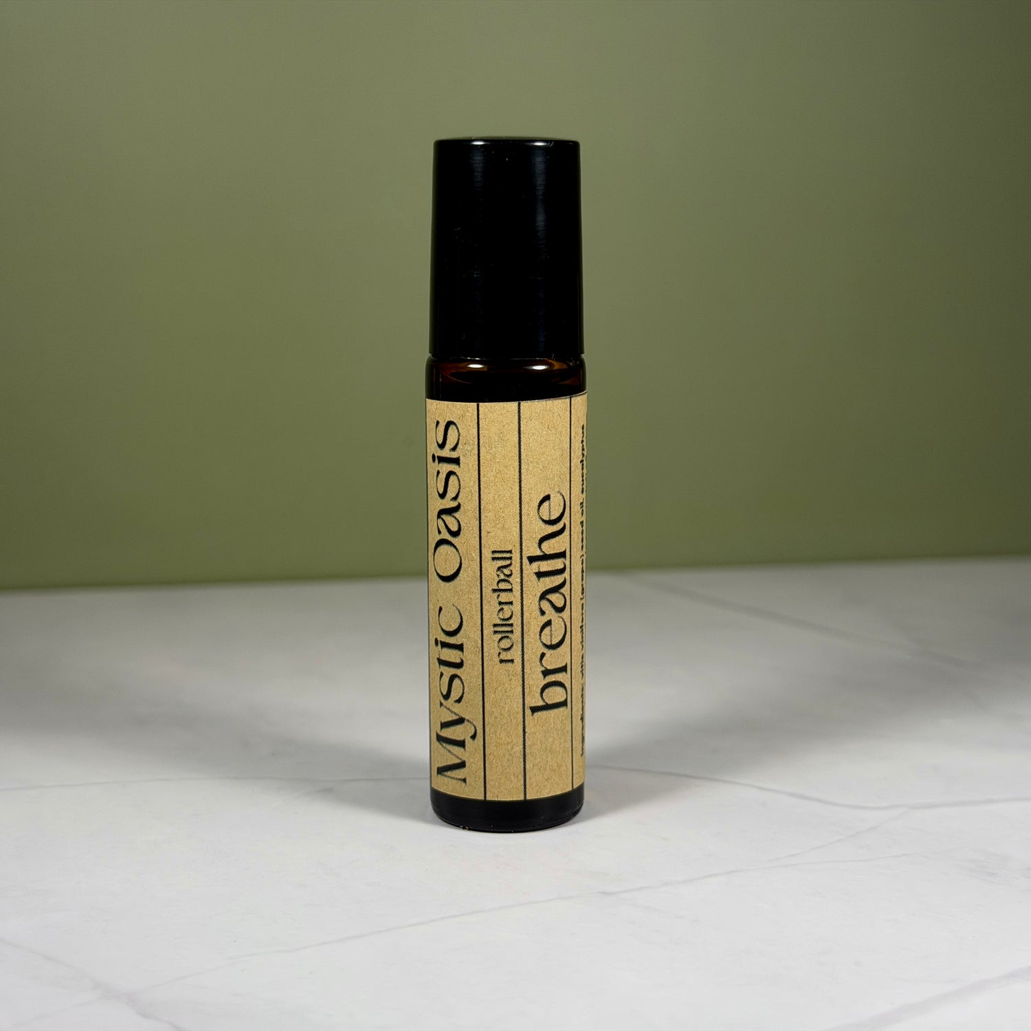 Rollerball bottle labeled 'breathe' by 'Mystic Oasis' on a white surface with a green background