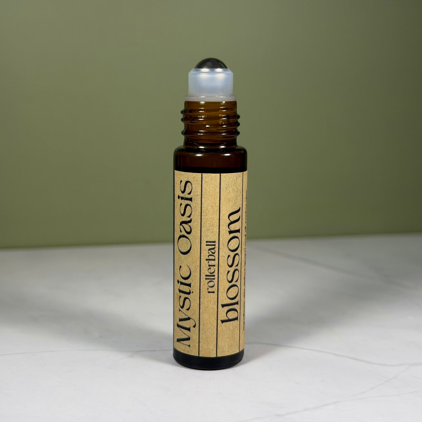 Rollerball bottle labeled 'Mystic Oasis' on a white surface with a green background