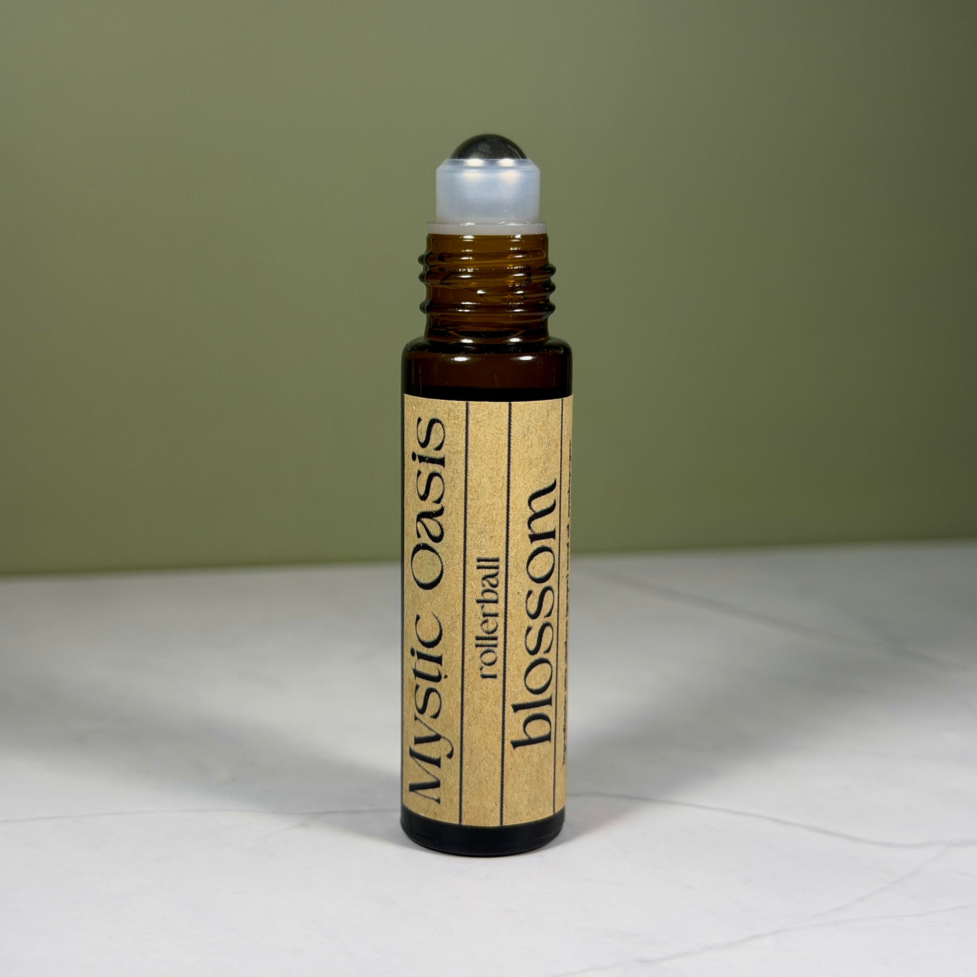 Rollerball bottle labeled 'Mystic Oasis' on a white surface with a green background