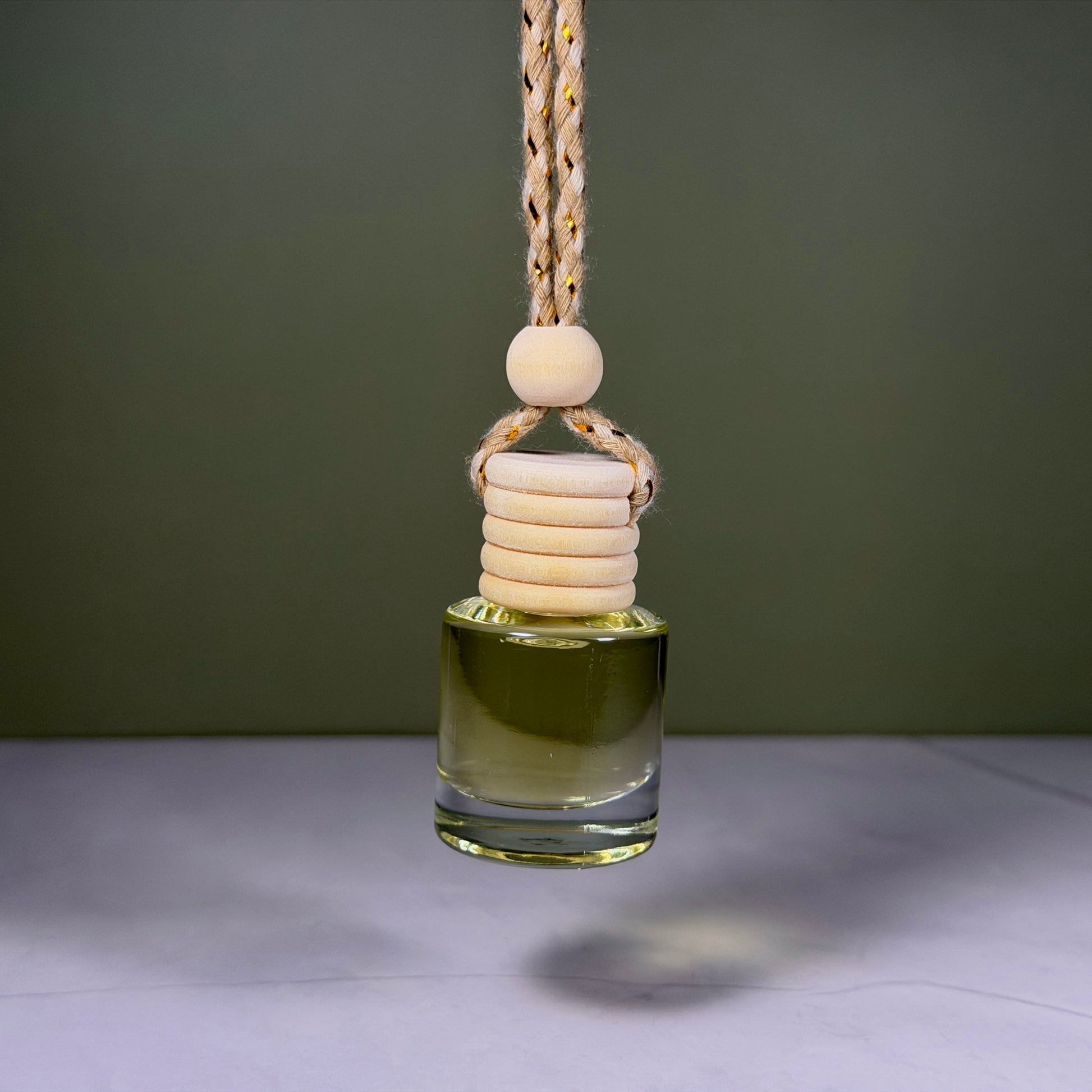 Glass diffuser bottle with wooden beads on a string against a dark background