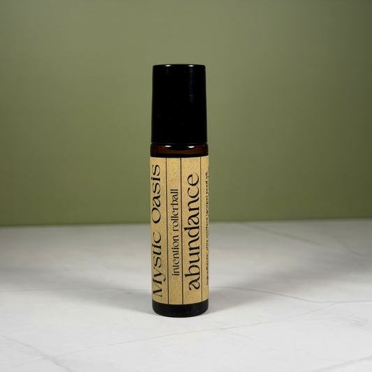 Roll-on bottle labeled 'Mystic Oasis' with 'abundance' on a white surface and green background