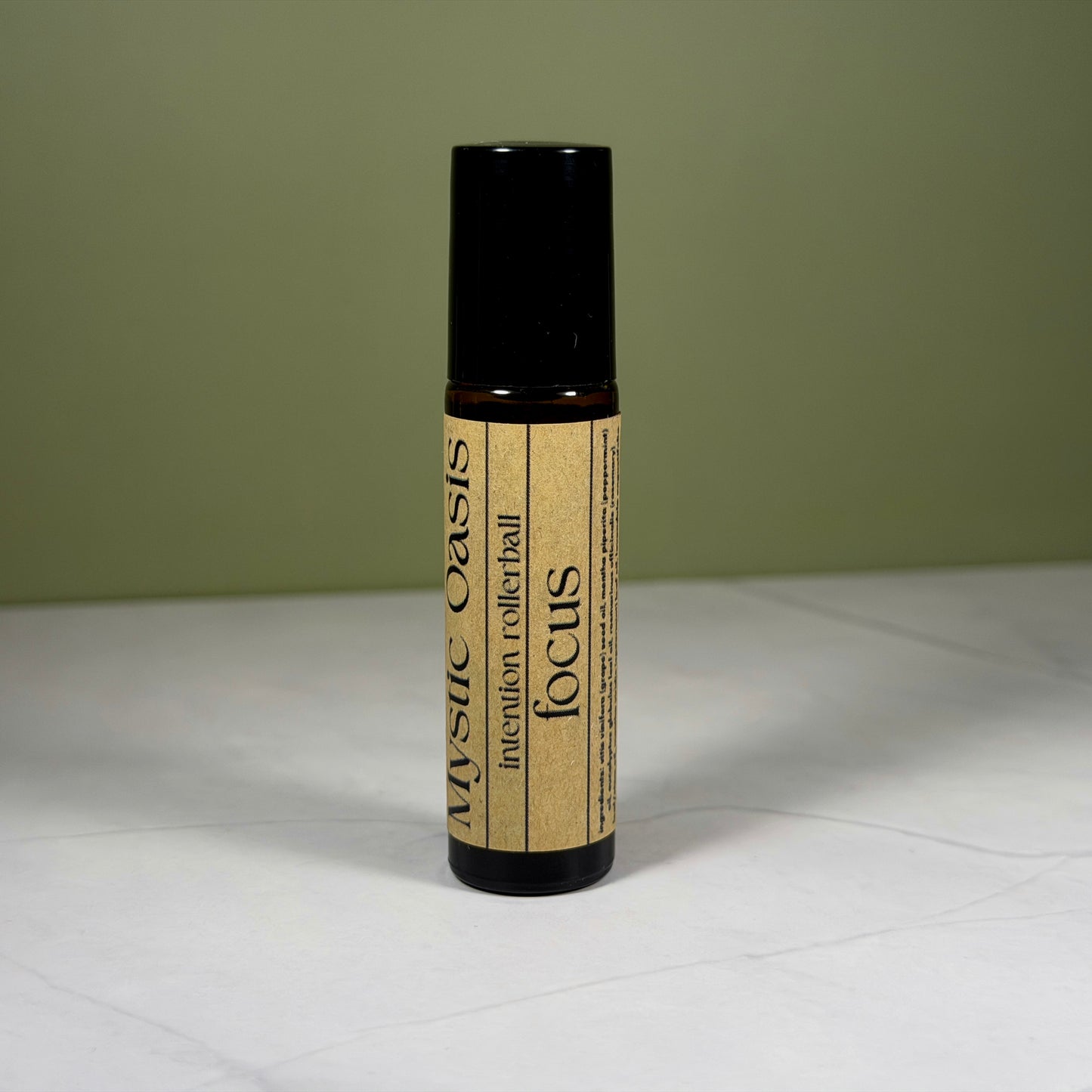 Rollerball labeled 'Mystic Oasis' with 'focus' on a white surface and green background