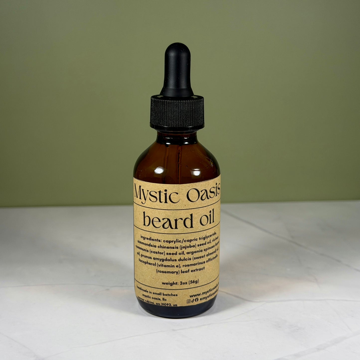 Bottle of Mystic Oasis beard oil with a dropper on a white surface and green background