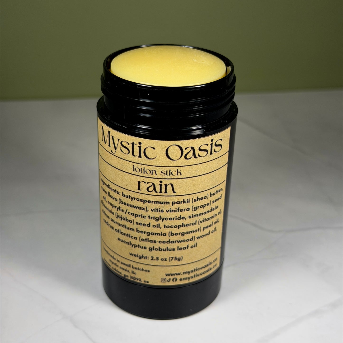 Mystic Oasis Rain lotion stick on a white surface with a green background